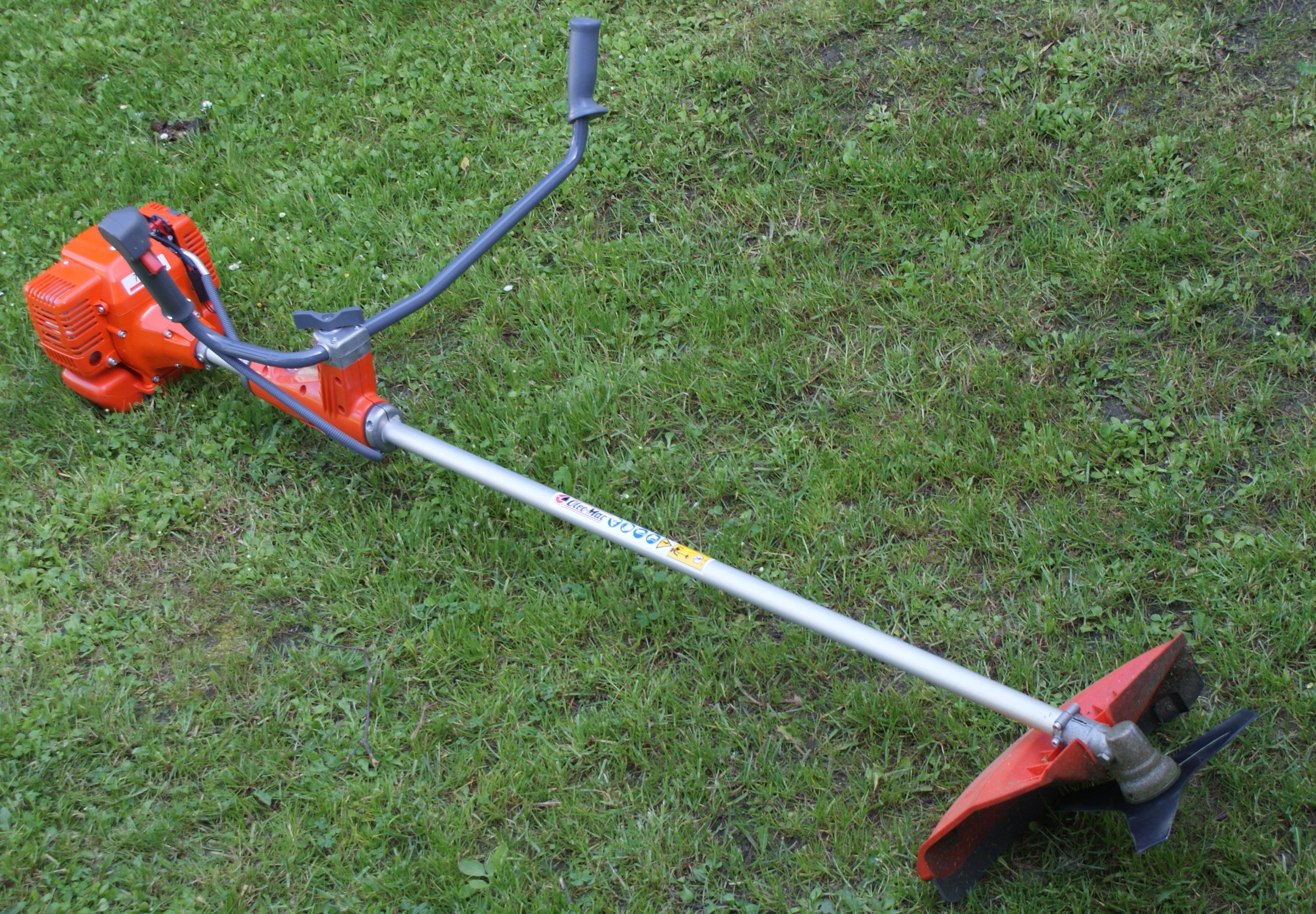 Illustrative example of a petrol brush cutter on grass